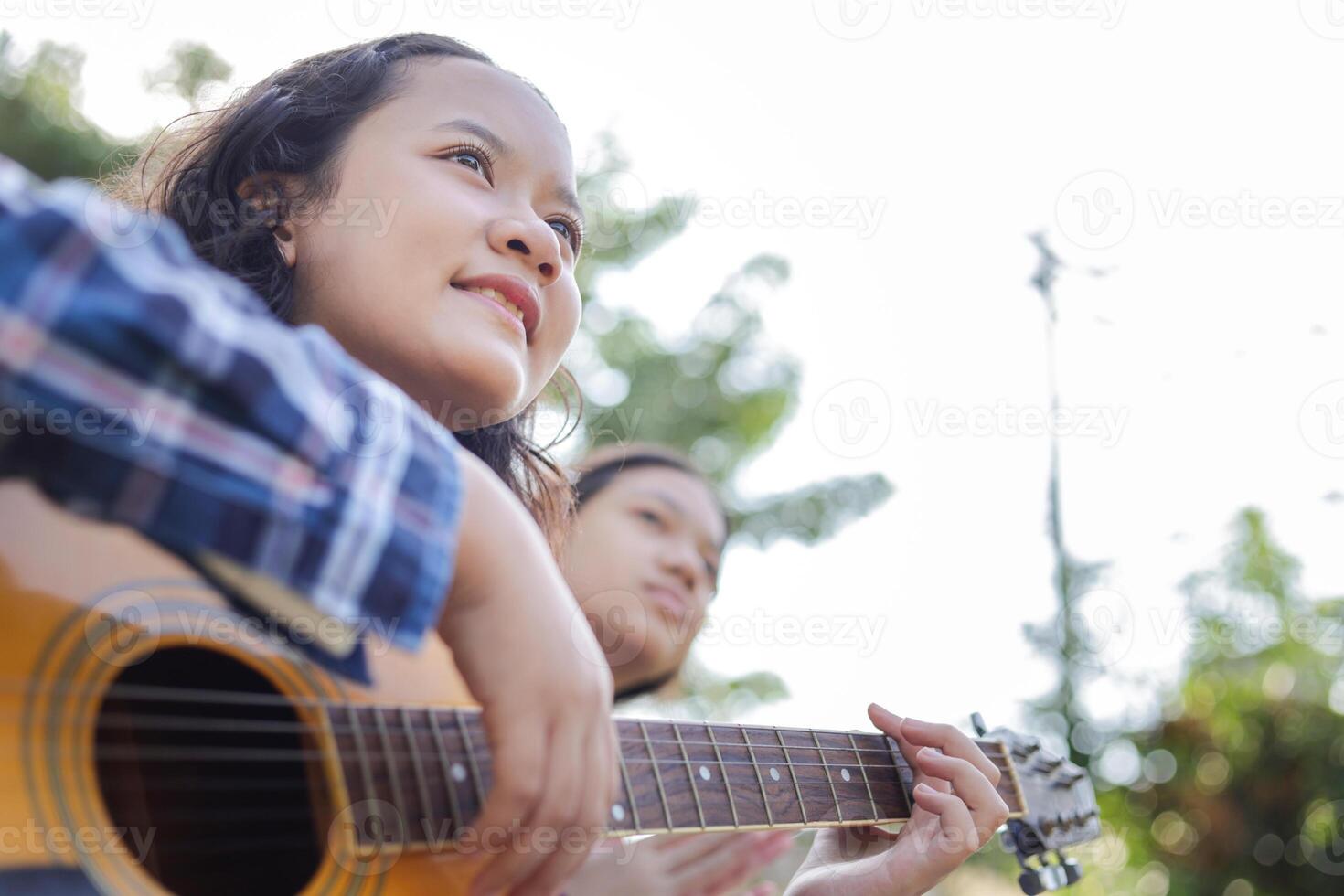 Asian kid girl and friend playing guitar in the park photo