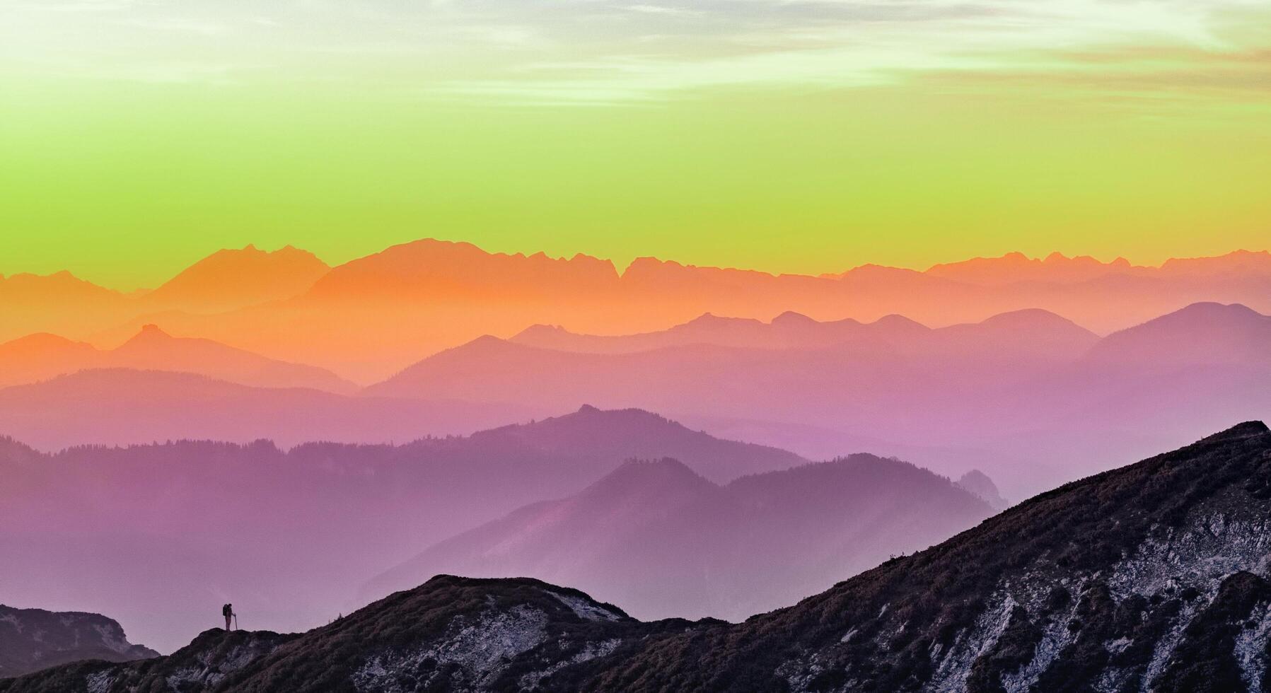 A person standing on top of a mountain at sunset photo