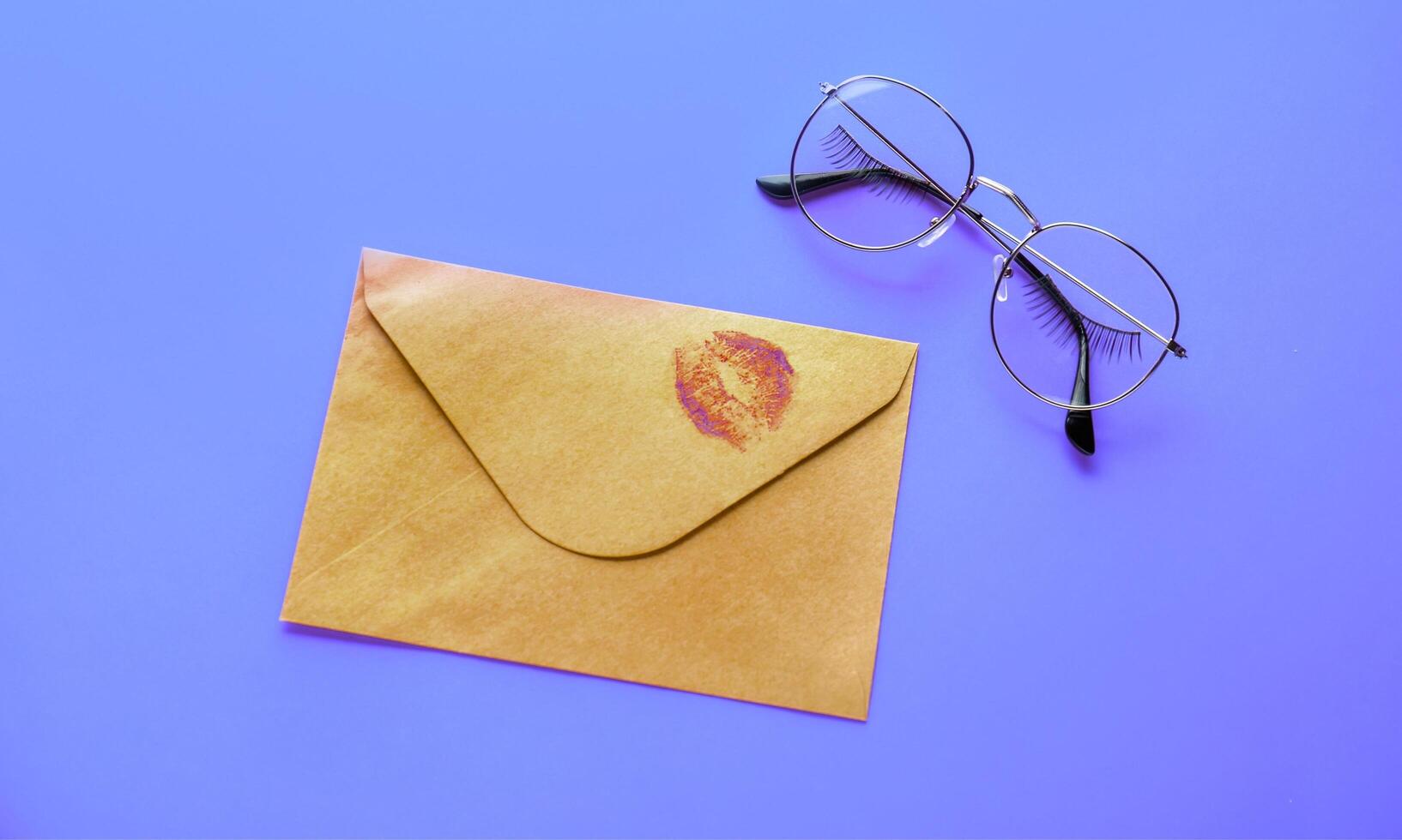 An envelope with a kiss on it and glasses on a purple background photo