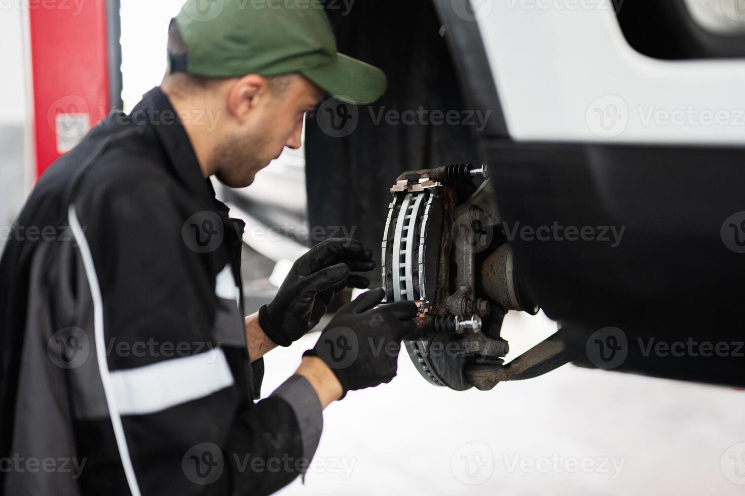 Mechanic inspecting car brake system in garage workshop photo