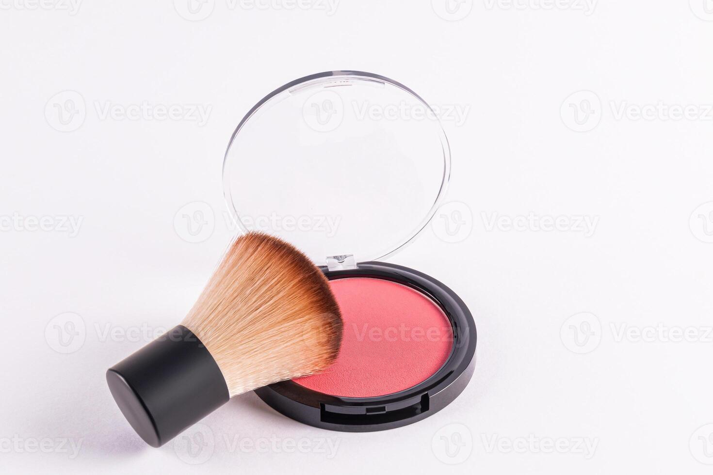 An open round pack of compact blush in a pink tone with a professional fluffy short makeup brush. isolated on a white background. A copy space. photo