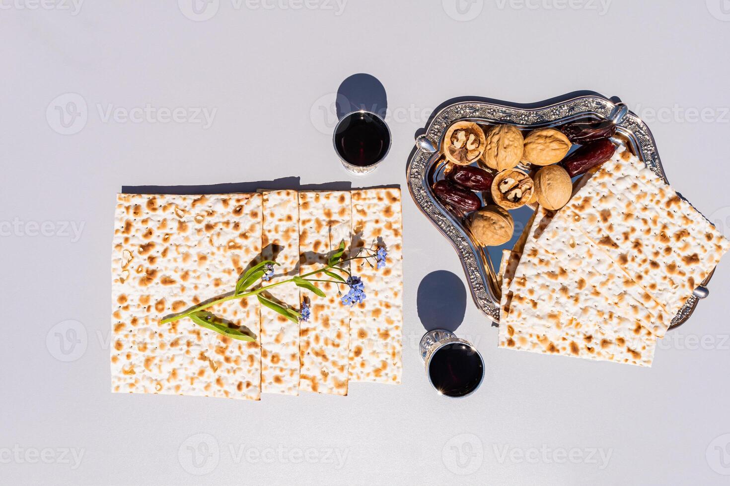 traditional Passover matzo bread and silver glasses of red wine on a gray background. walnuts, dates. The concept of the Passover holiday. top view. photo