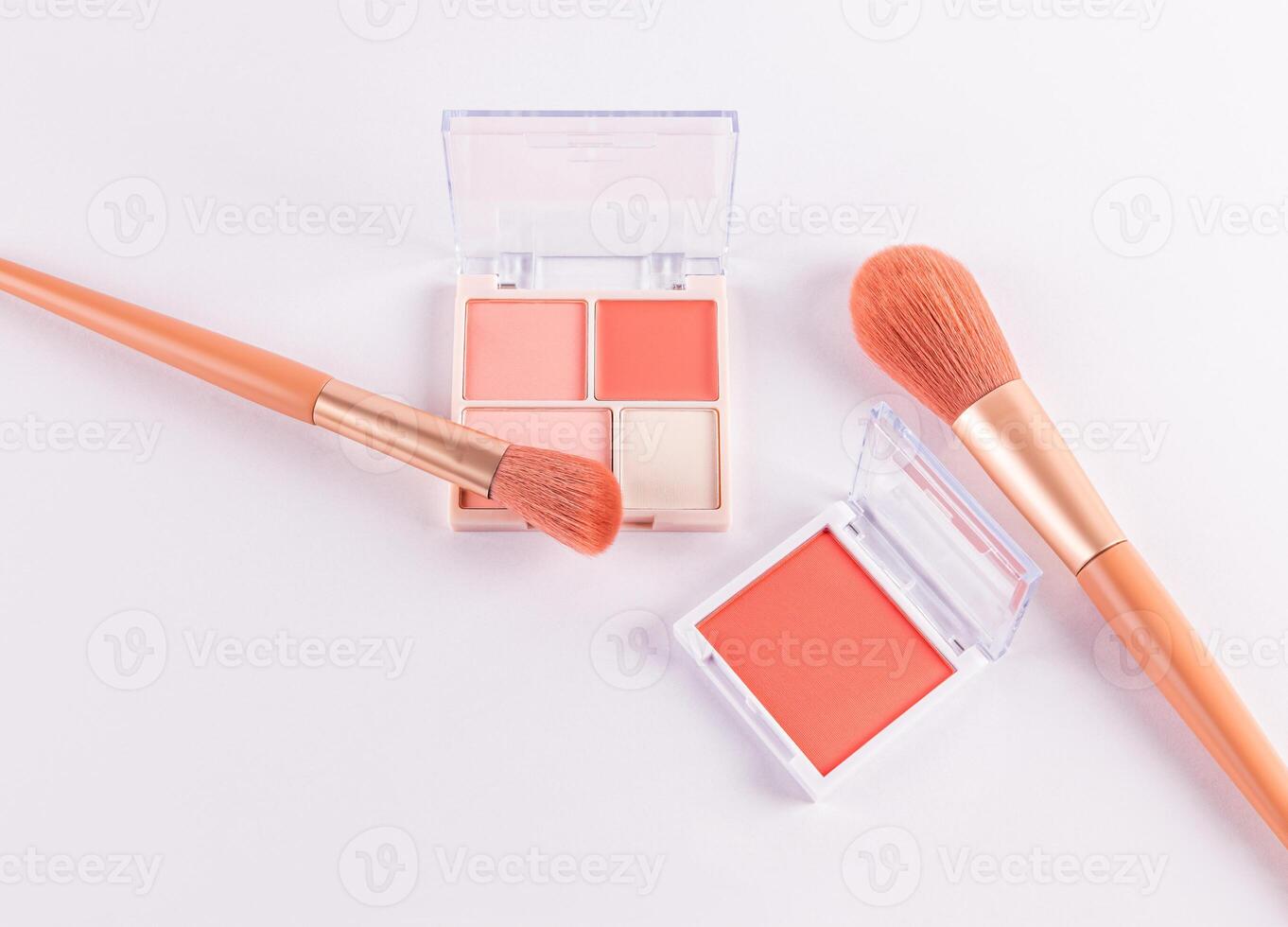 Two open packs with peach-tone blush and various light tones on a white background with two professional makeup brushes. top view. space for text. photo