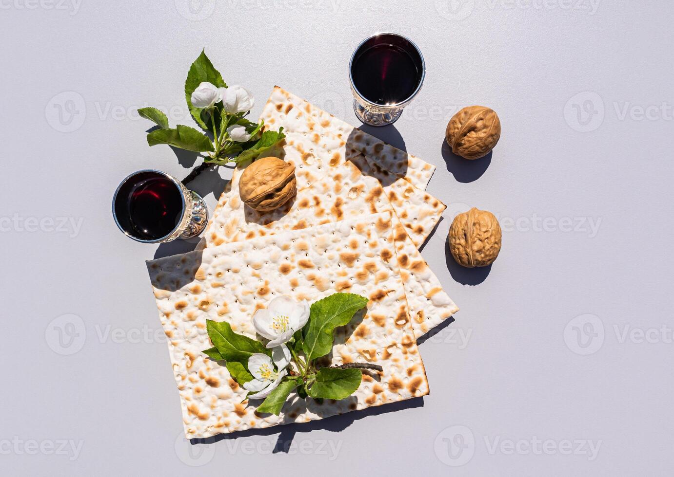 Festive composition of the Passover holiday. matzah, silver glasses with red wine, walnuts on a light background with twigs of blossoming apple trees. photo