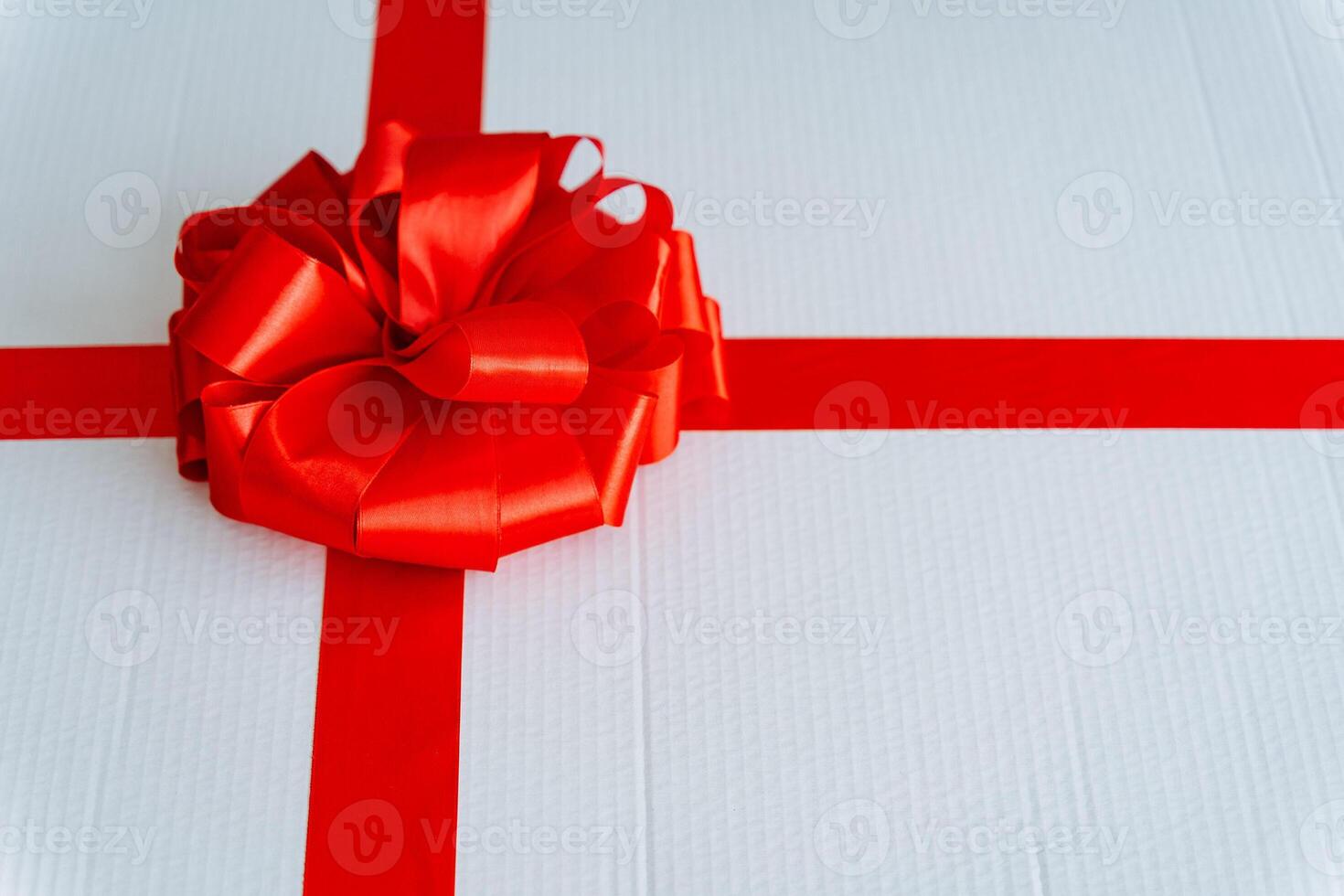 A white present adorned with a vibrant red ribbon and bow photo