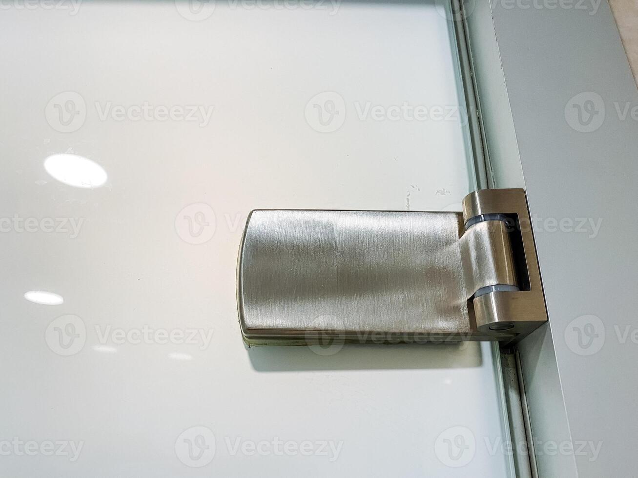 Close-up shot of metal door hinge on glass door with automotive exterior design in nickel finish photo