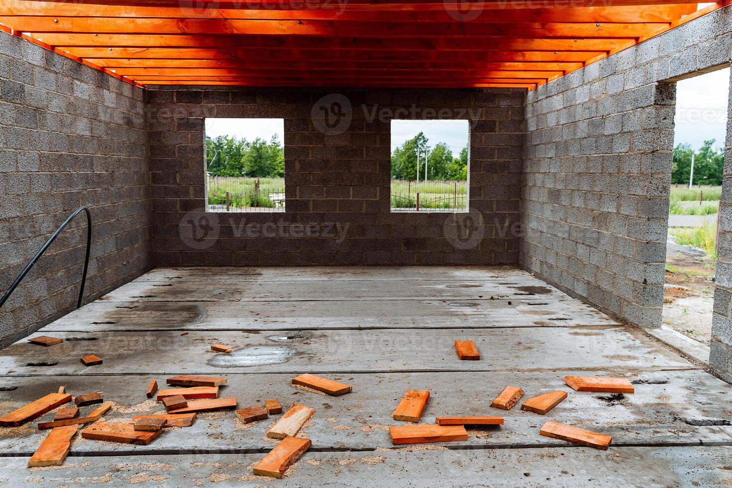 Currently, a garage is being constructed, featuring bricks scattered across the floor and a wooden ceiling overhead, contributing to the overall atmosphere of the building project photo