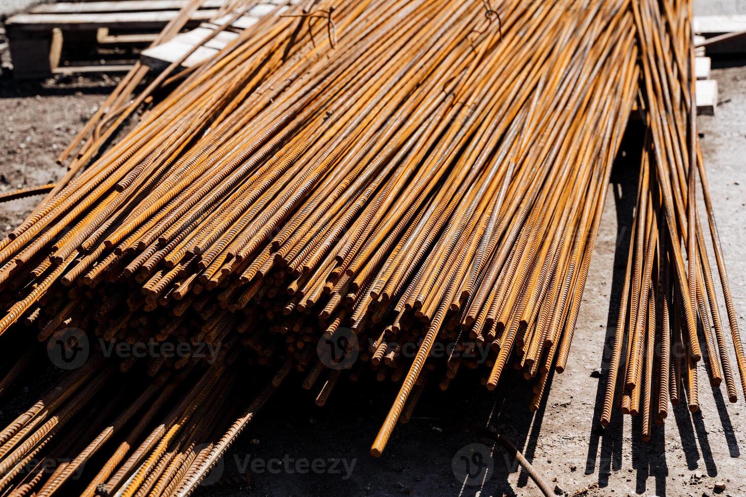 Closeup of rusty steel rebars at construction site creating a textured pattern. The heavy metal rods stack in an angled pile, providing reinforcement for the buildings foundation photo