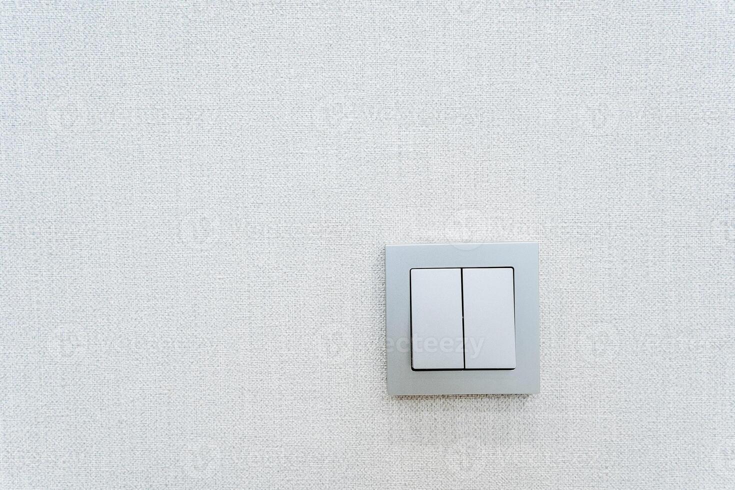 Rectangular white light switch on a white wall with symmetrical placement photo