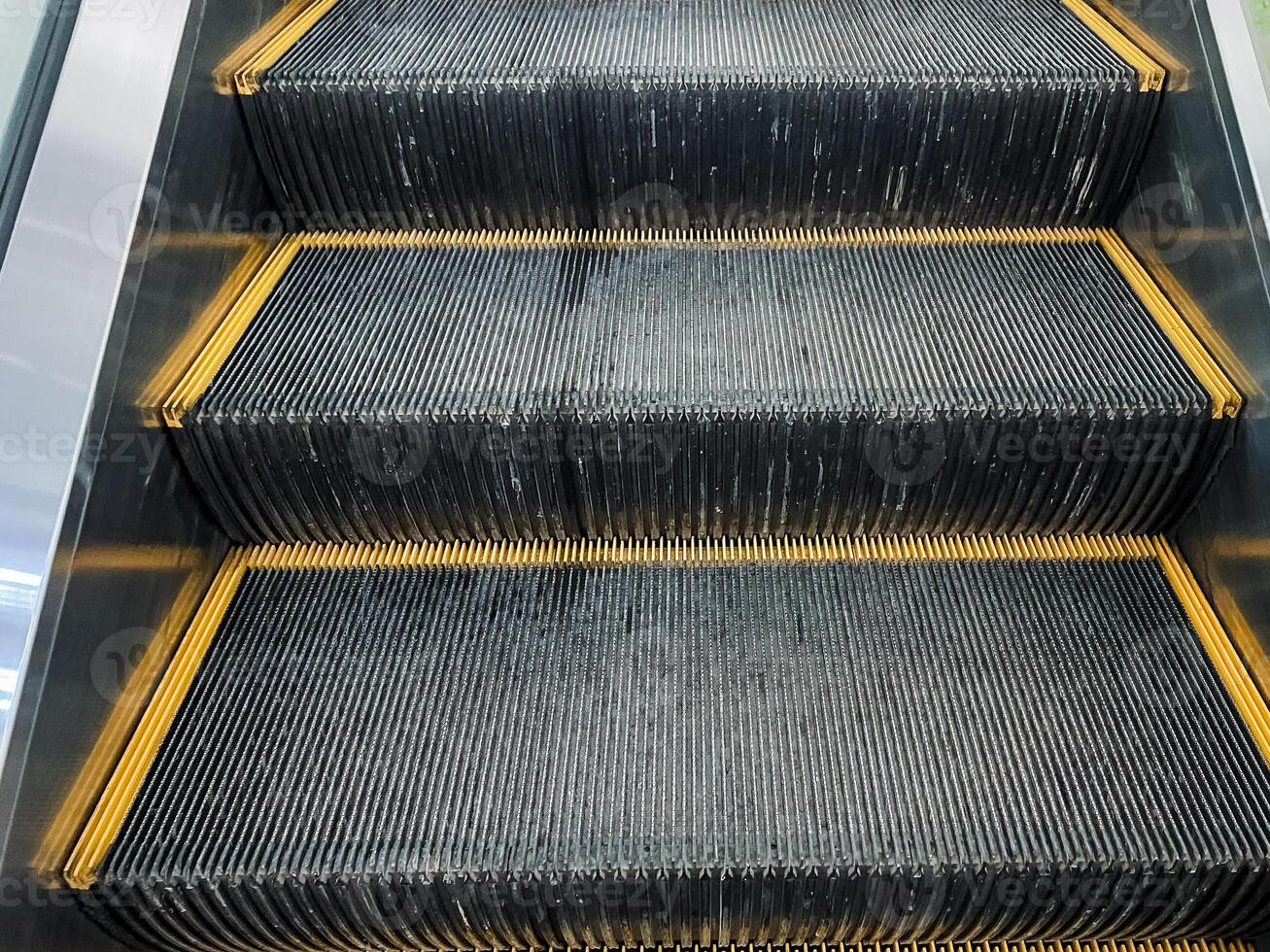 Closeup of a symmetrical escalator with yellow striped steps made of composite material photo