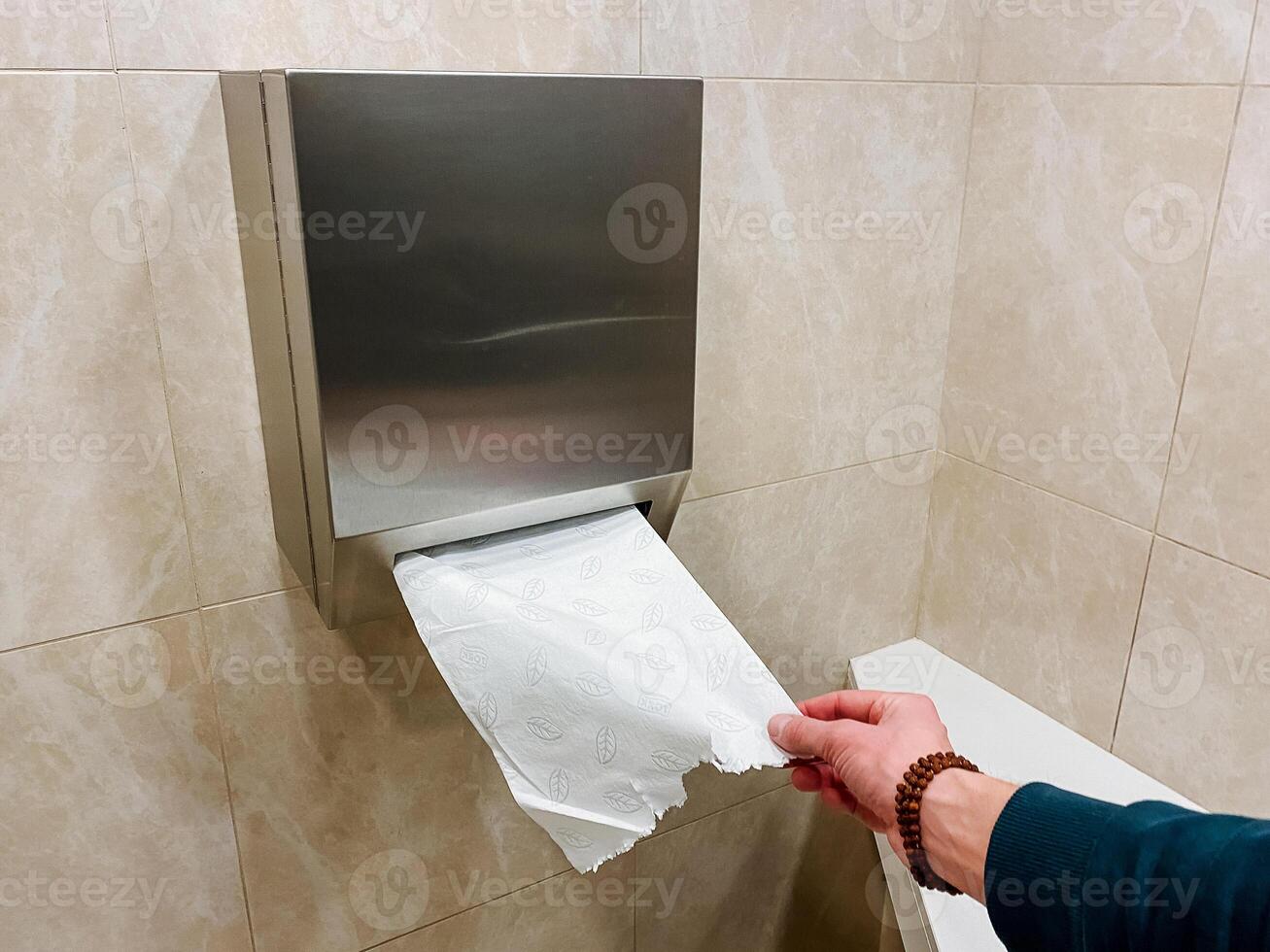 A person is using a paper towel dispenser in a bathroom photo