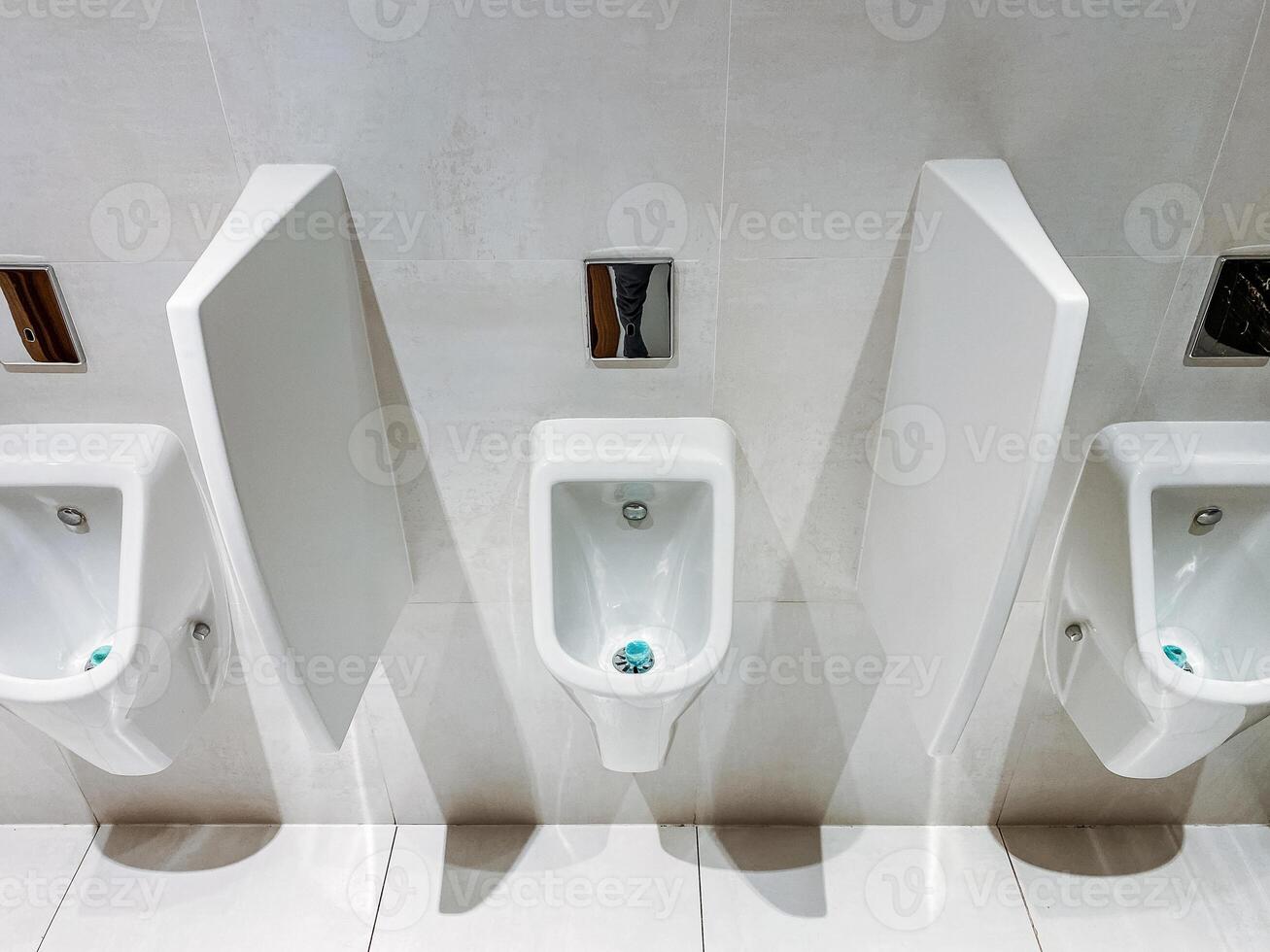 A row of urinals in a public restroom with dividers between them photo