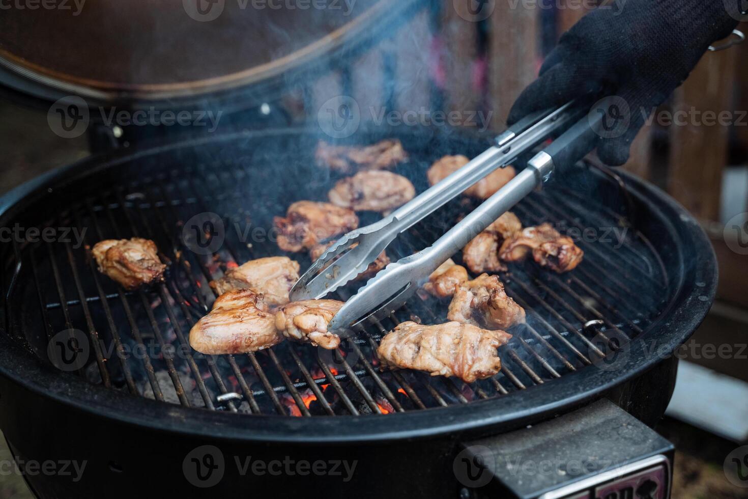 Delightful grilled chicken using tongs over charcoal for a perfect BBQ. Juicy, tender meat creates a flavorful meal for a delicious barbecue experience. Enjoy a culinary delight photo