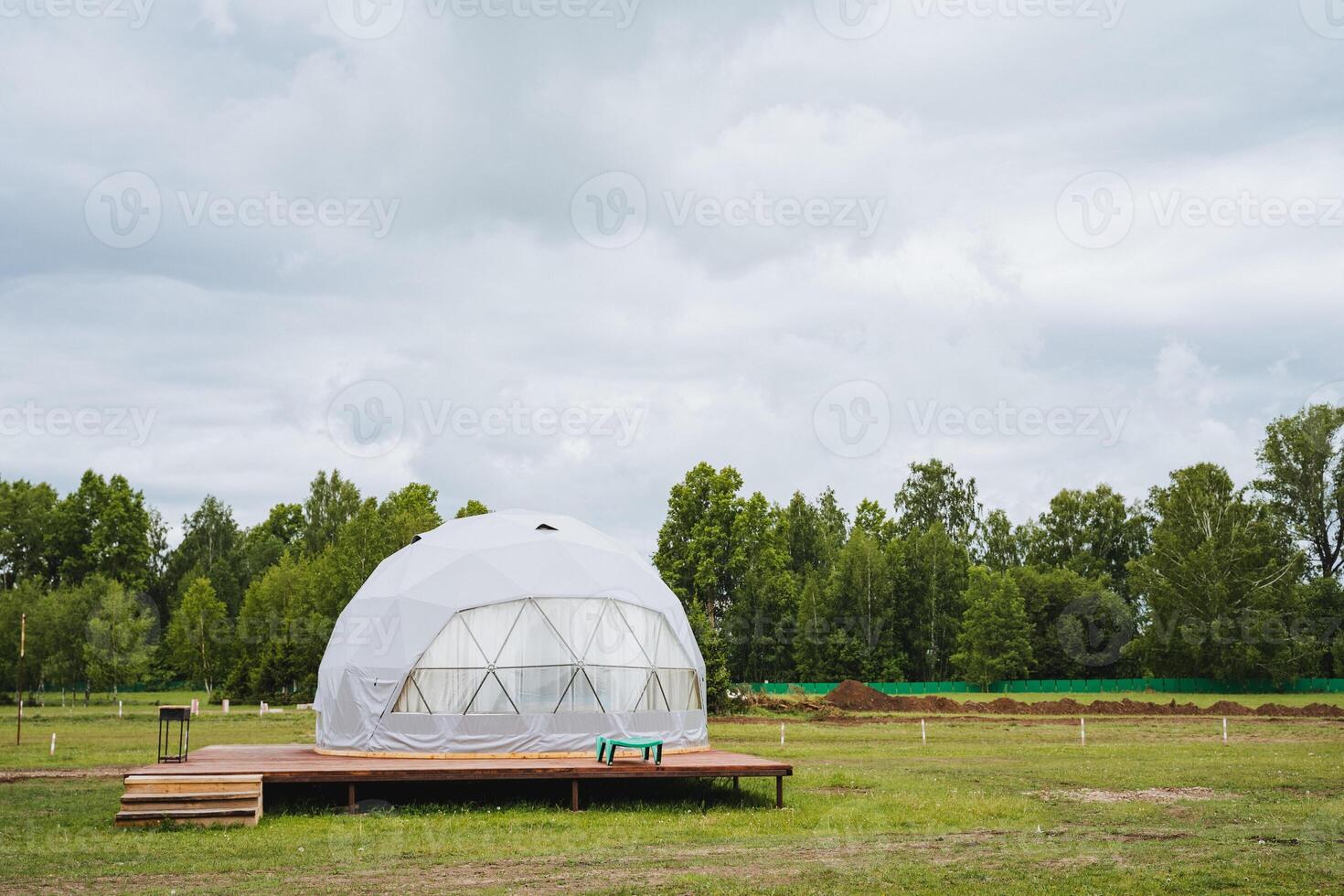 A unique geodesic ecofriendly transparent dome in a green field, perfect for ecotourism and glamping. It provides a pioneer landscape for a peaceful retreat in nature photo