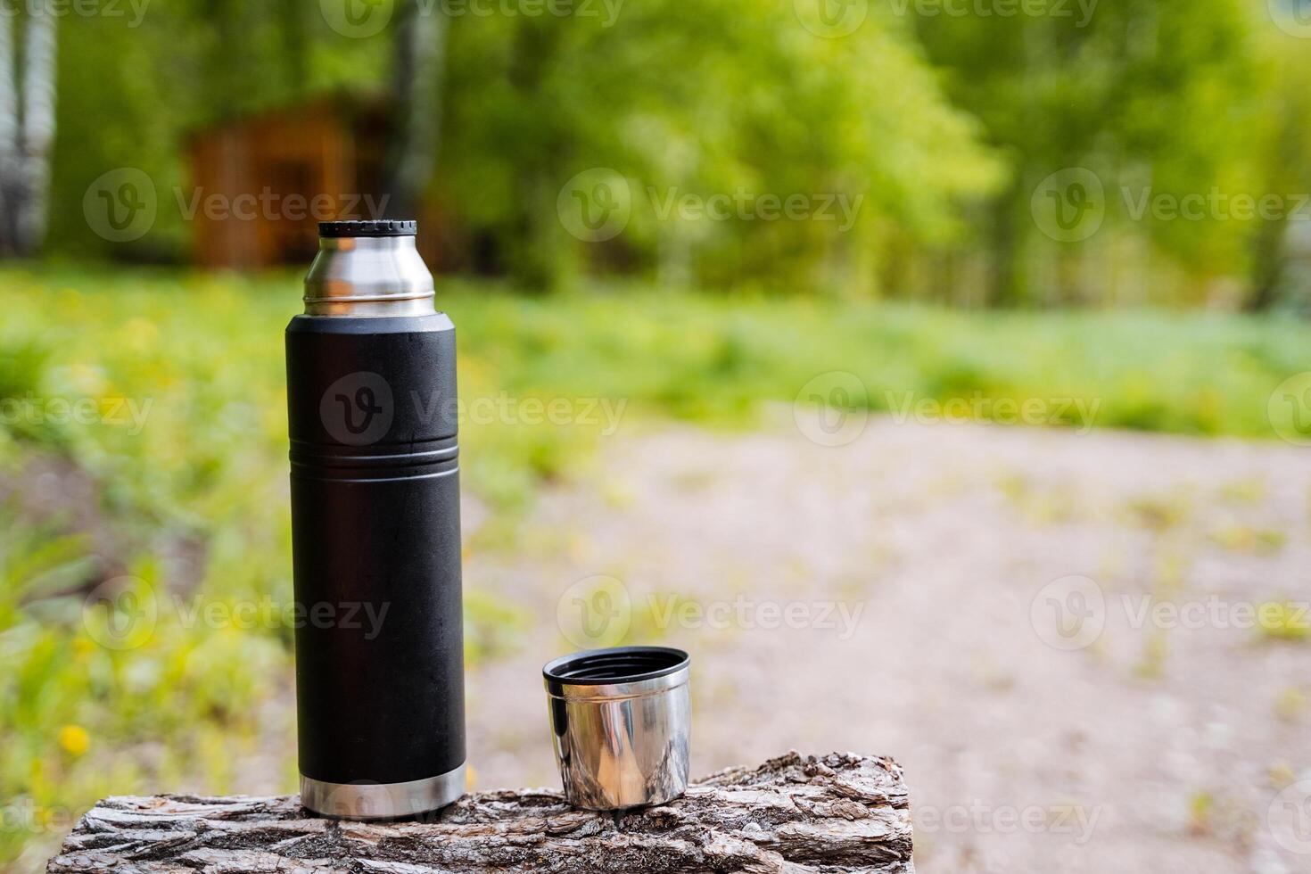Stainless steel thermos flask for outdoor adventures in the forest. Ecofriendly, sustainable, and reusable. Keeps beverages hot or cold. Perfect for camping, hiking, and picnics photo