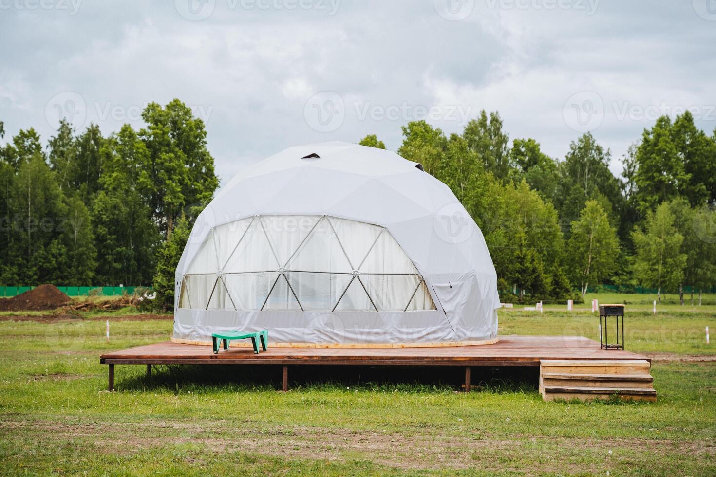 Experience a geodesic dome tent on a wooden platform in a tranquil natural setting, perfect for a serene and sustainable ecofriendly retreat amid verdant surroundings photo