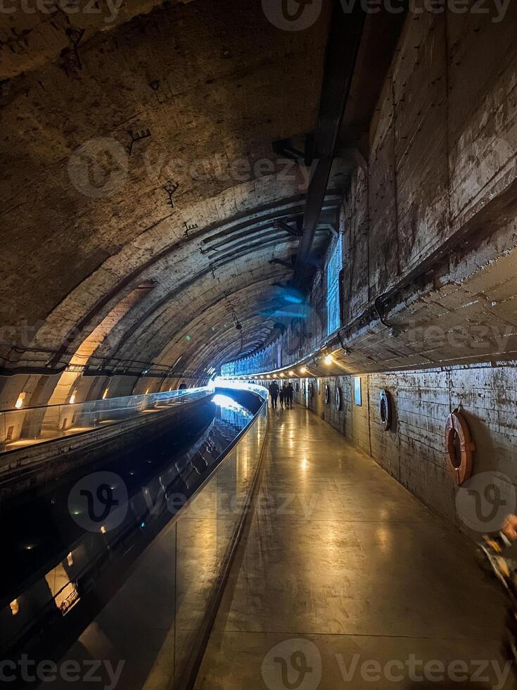 Picture in your mind a lengthy, dimlylit tunnel featuring a few scattered lights adorning the uneven walls, their soft illumination lending an unsettling yet mesmerizing ambiance photo