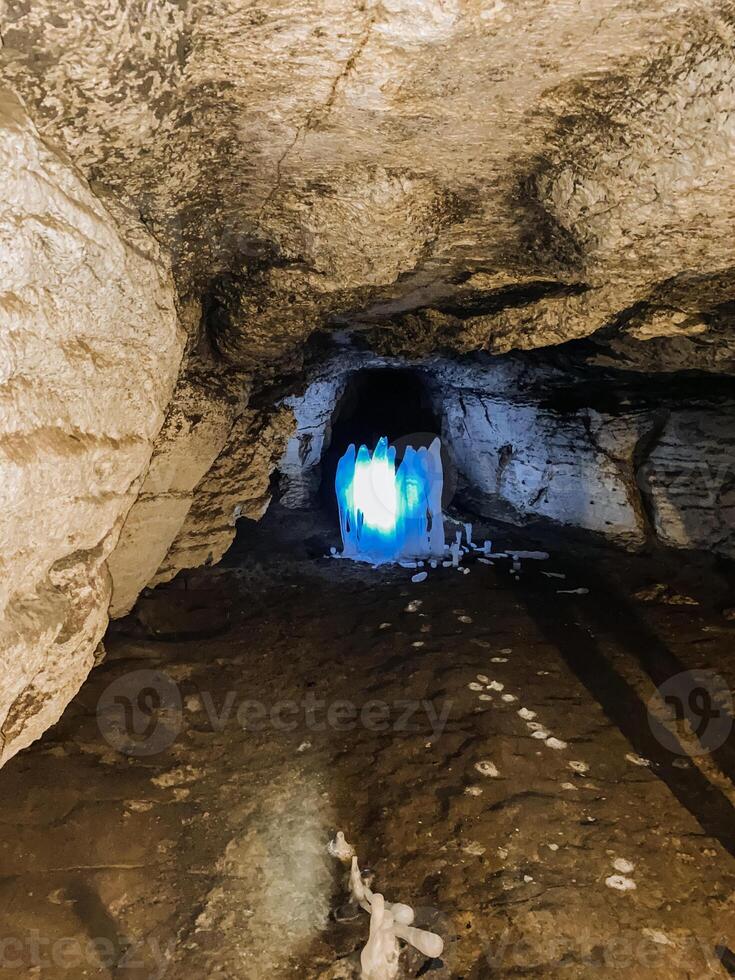 There is a cave that has a bright light shining out from within it, making it an intriguing and mysterious sight to behold, likely due to its unique geological features and formations photo