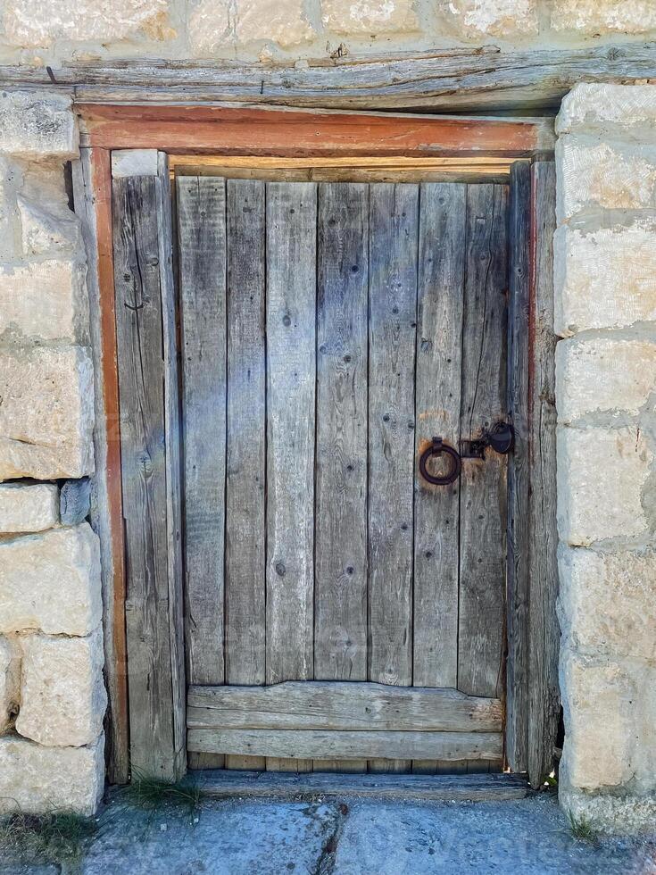 There is a beautifully crafted wooden door set into a sturdy stone wall, and it features a key resting on its surface, suggesting a sense of mystery and potential security photo