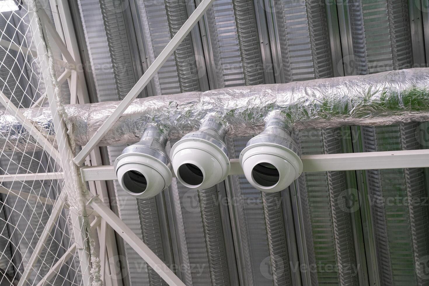 In the interior space of the building, there are three security cameras that are strategically hanging from the ceiling to monitor the area effectively and ensure security photo