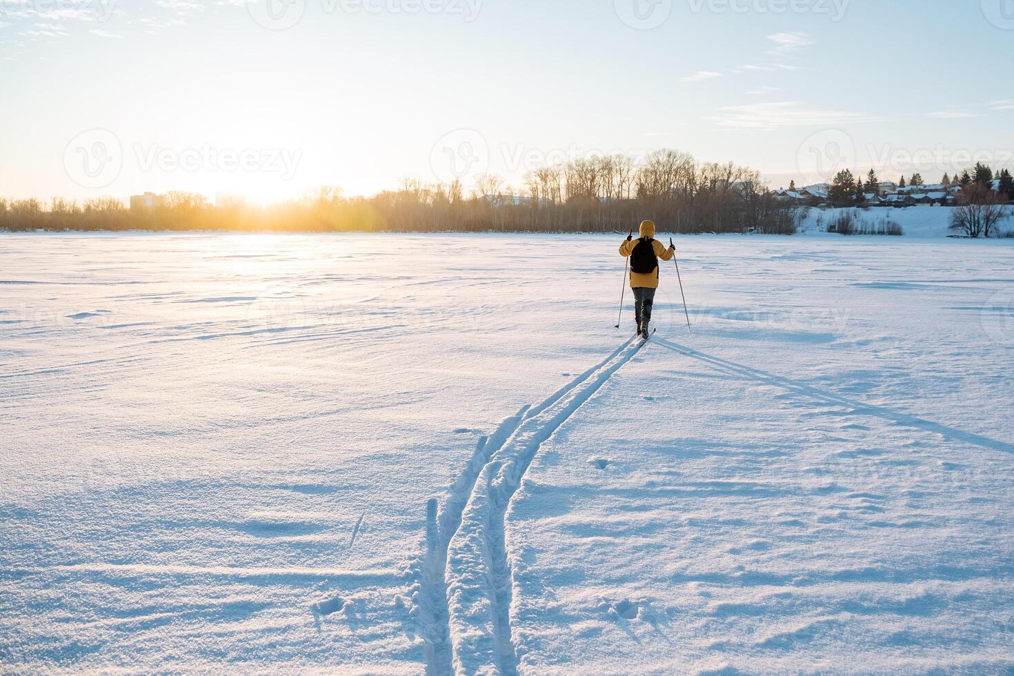Ski tracks in the snow, man walking on cross-country skis in deep snow, evening skiing at sunset, winter activity, outdoor training. photo