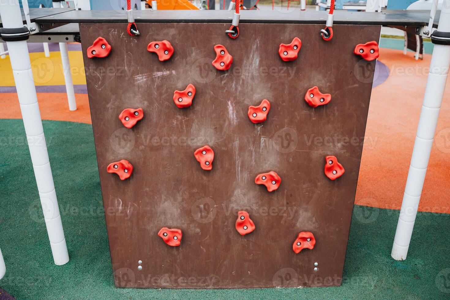 In a cheerful, lively playground, a vibrant climbing wall adorned with bright red holds captivates children, promoting fitness, social interaction, and essential life skills through play photo