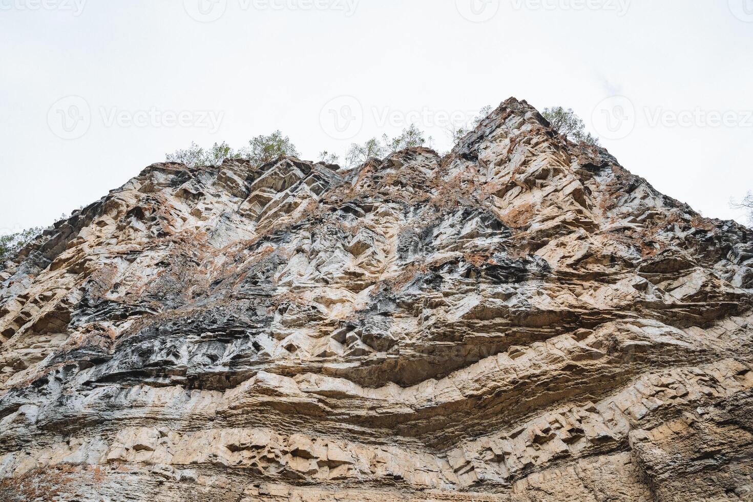 The image features a closeup view of a rocky mountain portrayed against a clean, white background that contrasts beautifully with the intricate details of the rock formation photo