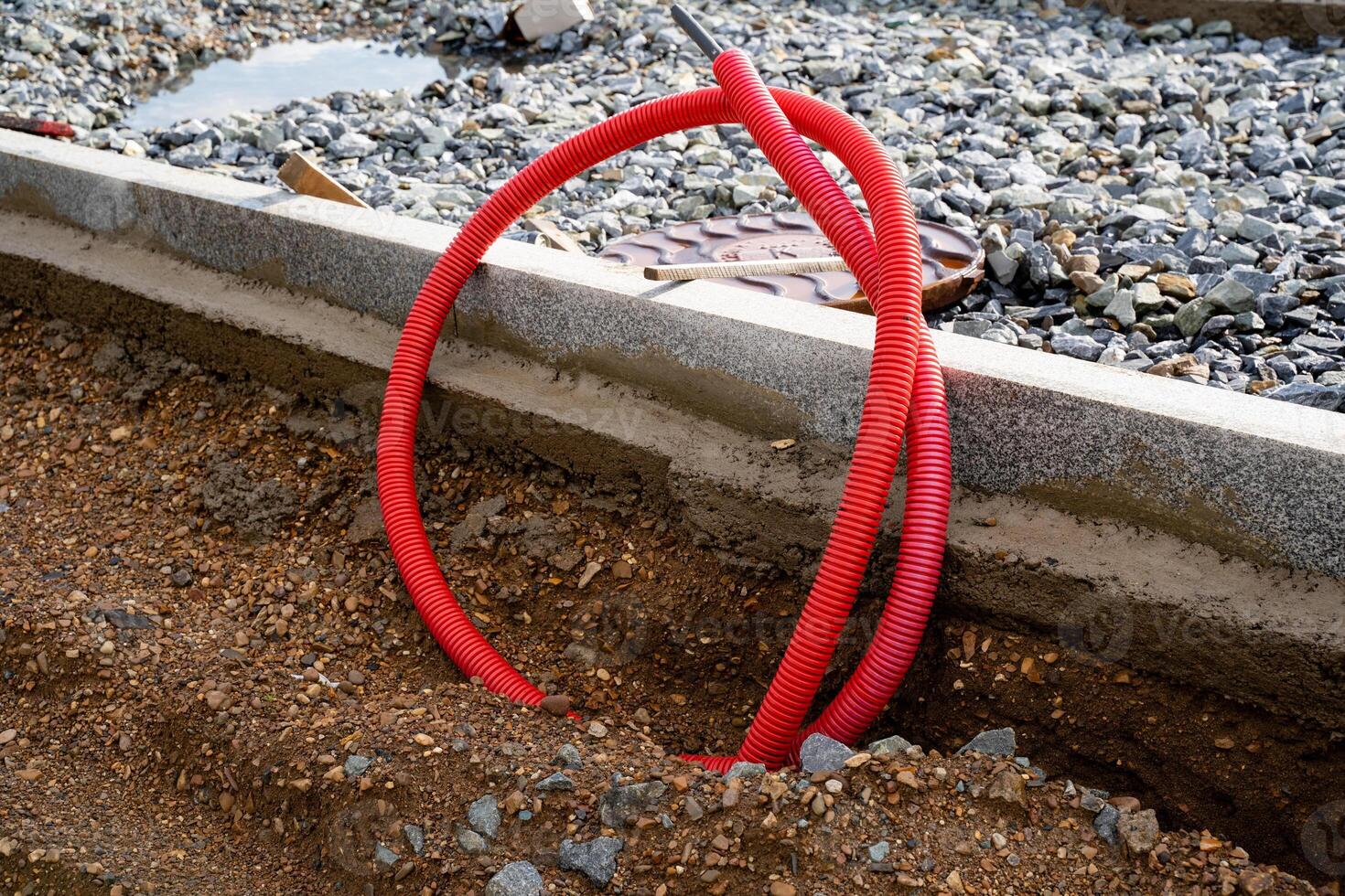 A vibrant red pipe is casually laying on the dirtcovered ground, blending in with the natural surroundings, creating an interesting visual contrast against the earthy tones and textures photo