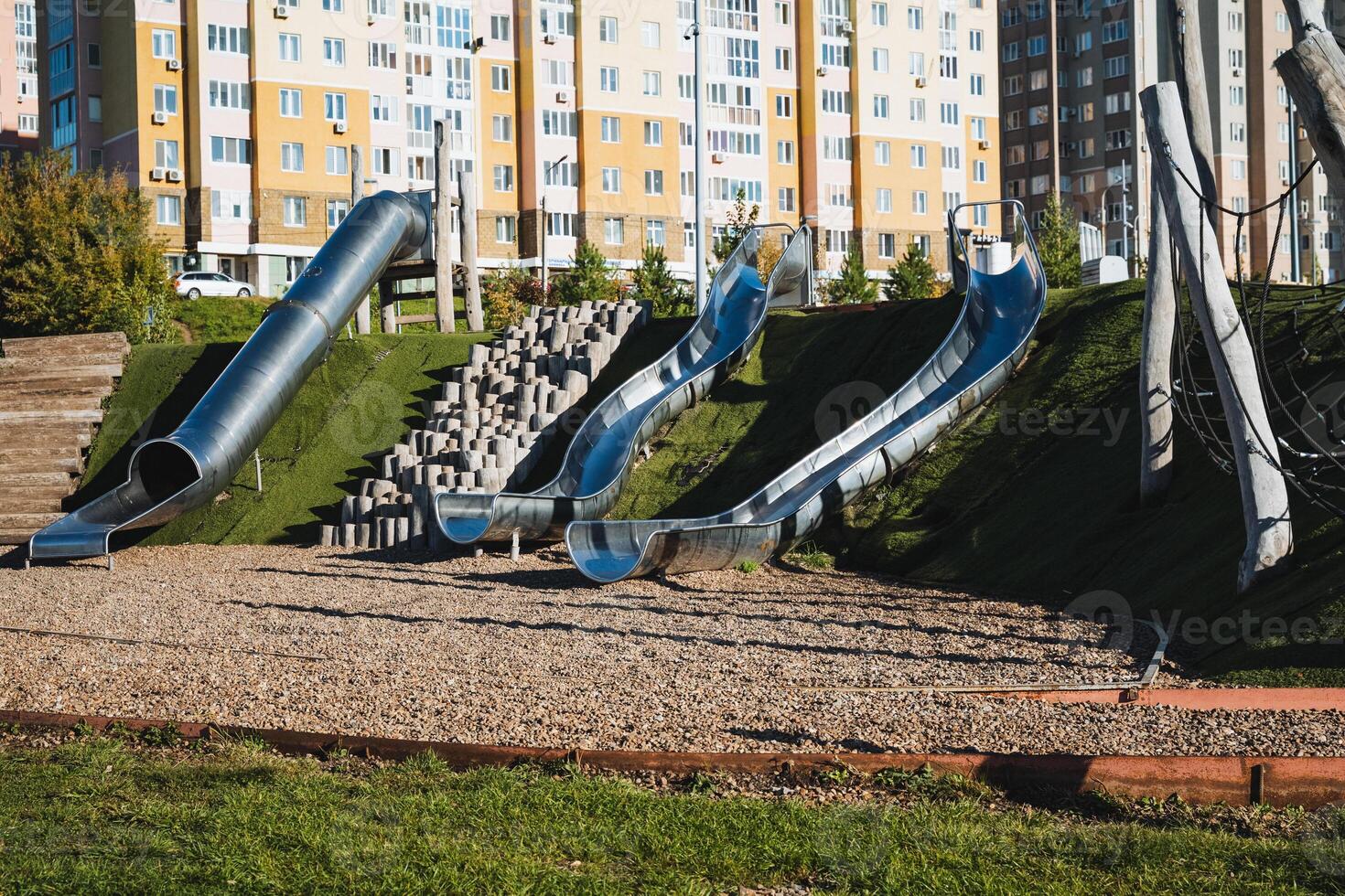 A vibrant playground featuring a colorful slide and sturdy stairs, conveniently located in front of a tall building, providing a fun and enjoyable space for children to play photo