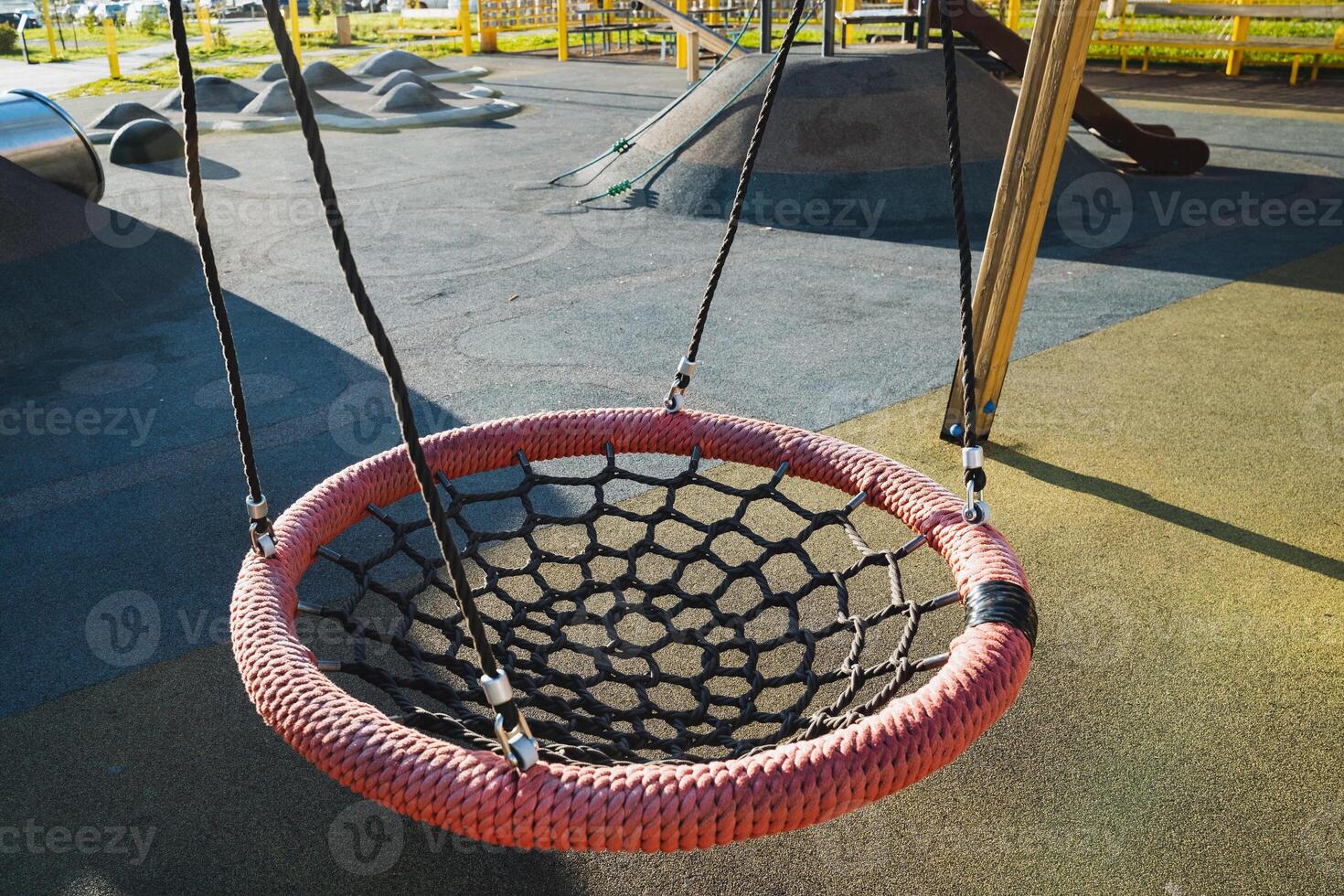 A bright red net swing is currently hanging in the playground, ready for children to enjoy their leisure time. It is a lovely spot for fun and playful events in the open air photo