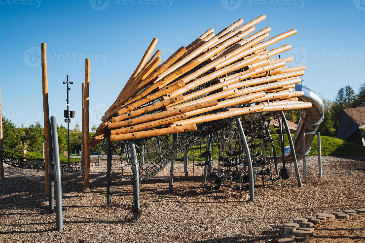 In a vibrant playground, children can explore a sturdy wooden structure along with a high slide, creating a secure and enjoyable environment for various outdoor activities and play photo