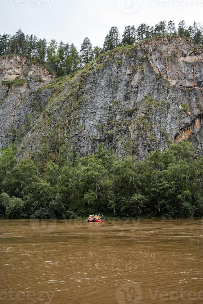 A serene scene with a boat peacefully floating on the river against a tranquil cliff backdrop, forming a picturesque natural landscape with water, mountains, and landforms photo
