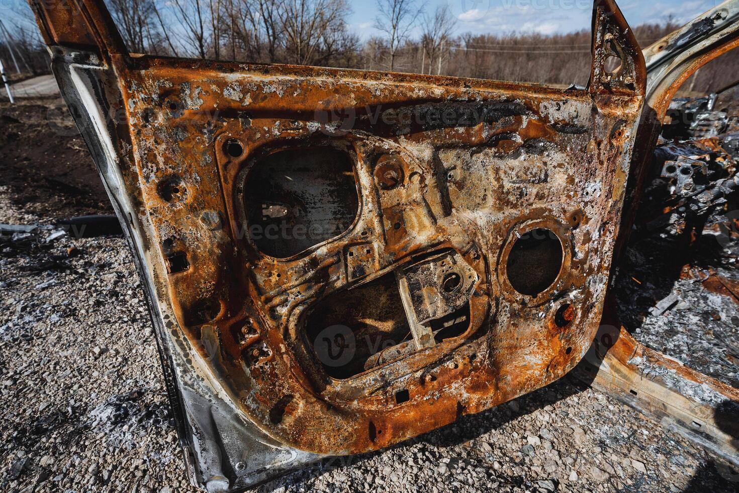 A burnt car door, a rusty car interior, a piece of iron. photo