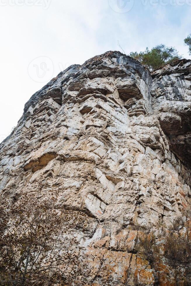 In the scenic view, a large rock formation majestically stands out against a backdrop of a bright blue sky, showcasing the beauty of nature. The scene captivates with its stunning visuals photo