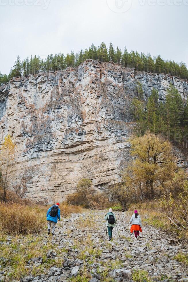 Adventurous Hikers Engaging in an Exciting Exploration and Discovering the Stunning Scenic Rocky Cliffside Amidst the Beautiful Autumn Landscape photo