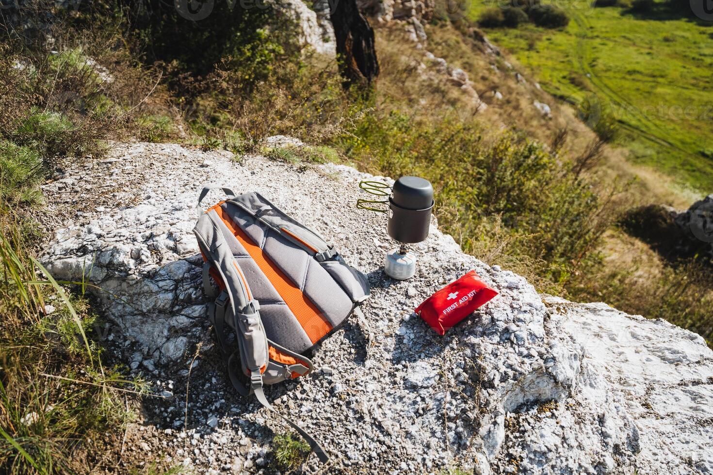 A colorful backpack is resting atop a large rock beside a first aid kit photo