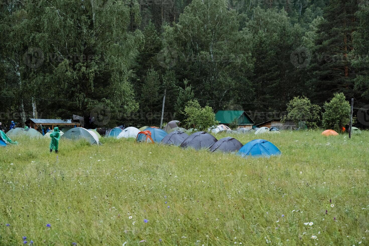 A cluster of tents is set in a peaceful grassy field embraced by rich trees and a charming natural scenery. Its an ideal setting for outdoor activities and unwinding in tranquility photo