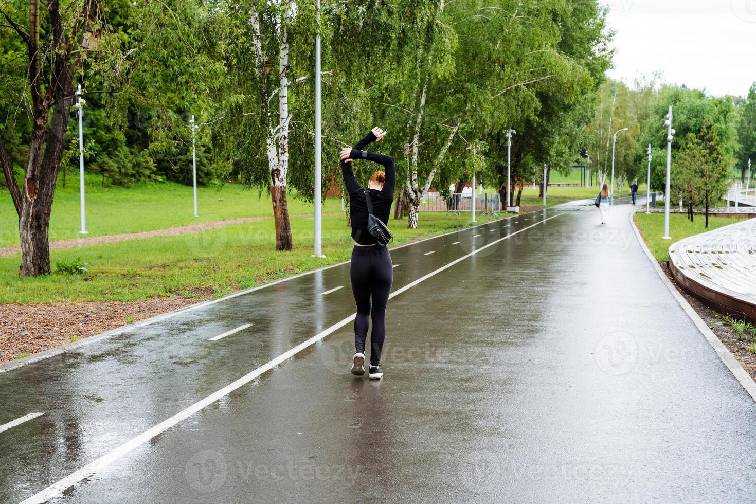 An individual is joyfully roller skating on a wet park pathway, engaging in outdoor recreation amidst the greenery and nature, embodying a sense of freedom and leisure photo
