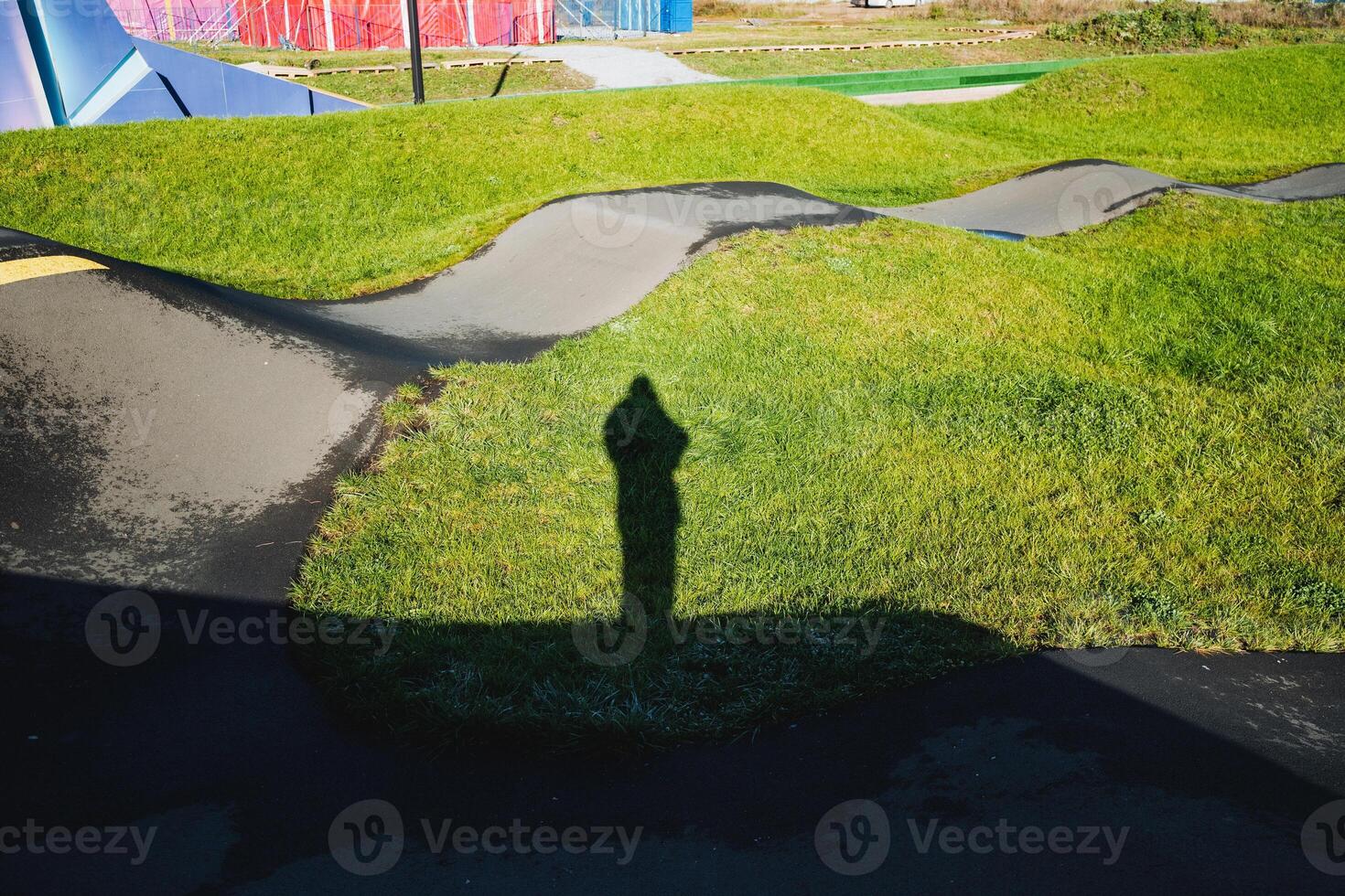 A long shadow of a person is seen standing amidst the tall grass, creating a distinctive silhouette against the backdrop of natures greenery, emphasizing the contrast in the landscape photo