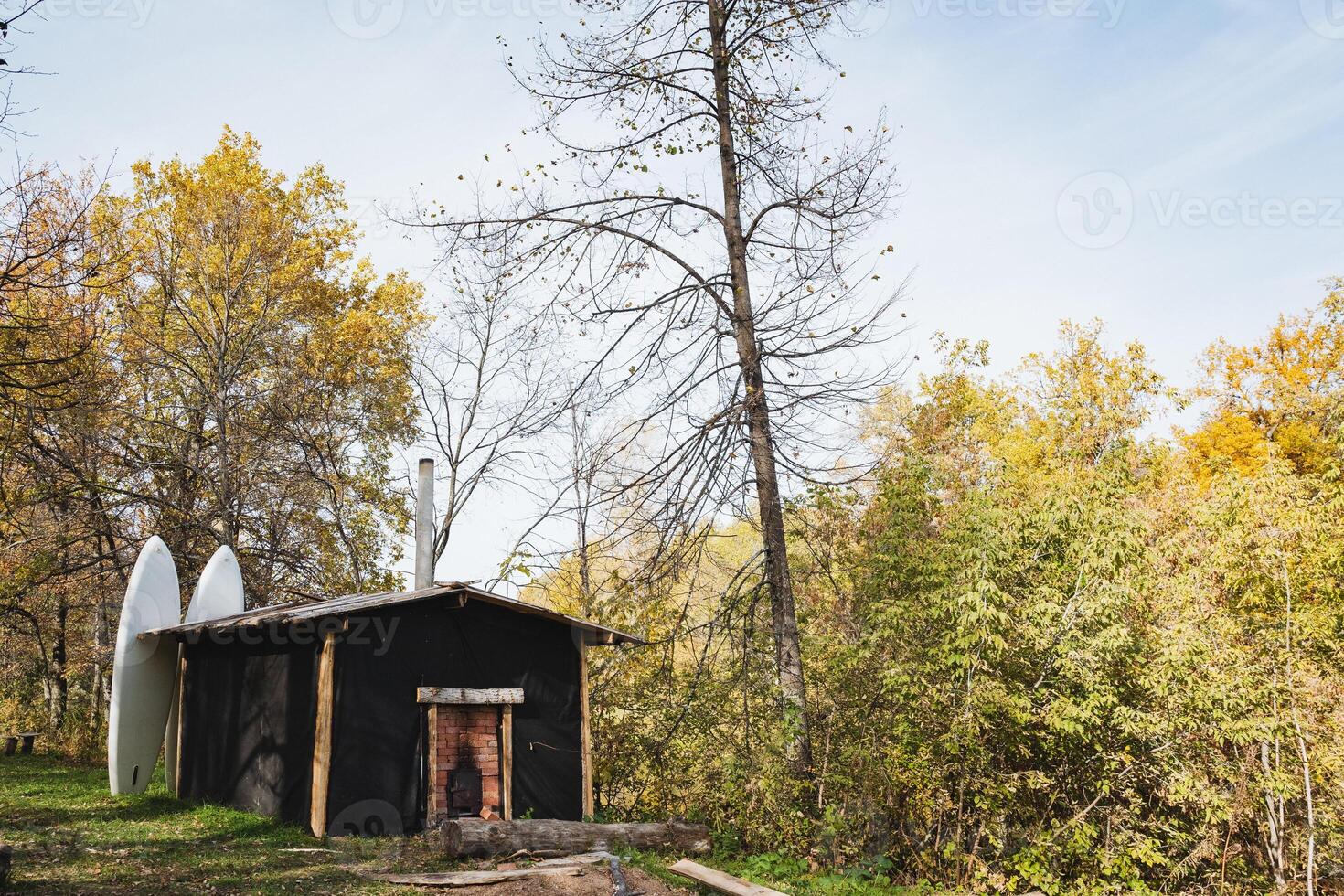 A small, quaint black building is nestled in the heart of a dense and serene forest, surrounded by towering trees and lush greenery, providing a peaceful retreat from the outside world photo