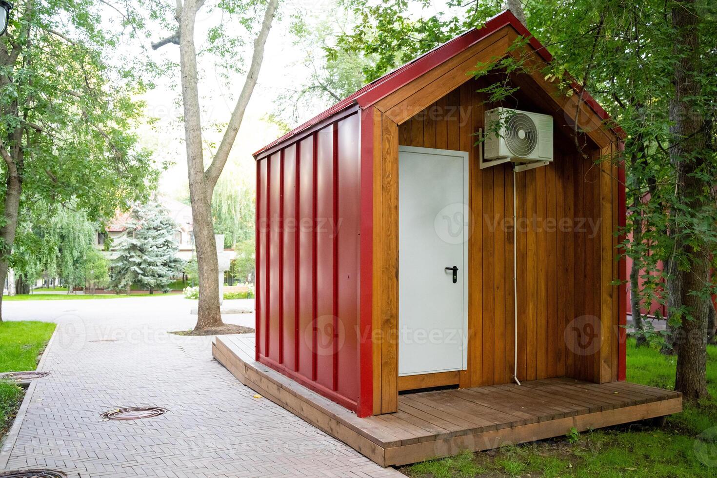 This modern, contemporary tiny house beautifully combines wooden and metal design elements, elegantly set amidst vibrant greenery in a tranquil, peaceful park setting photo