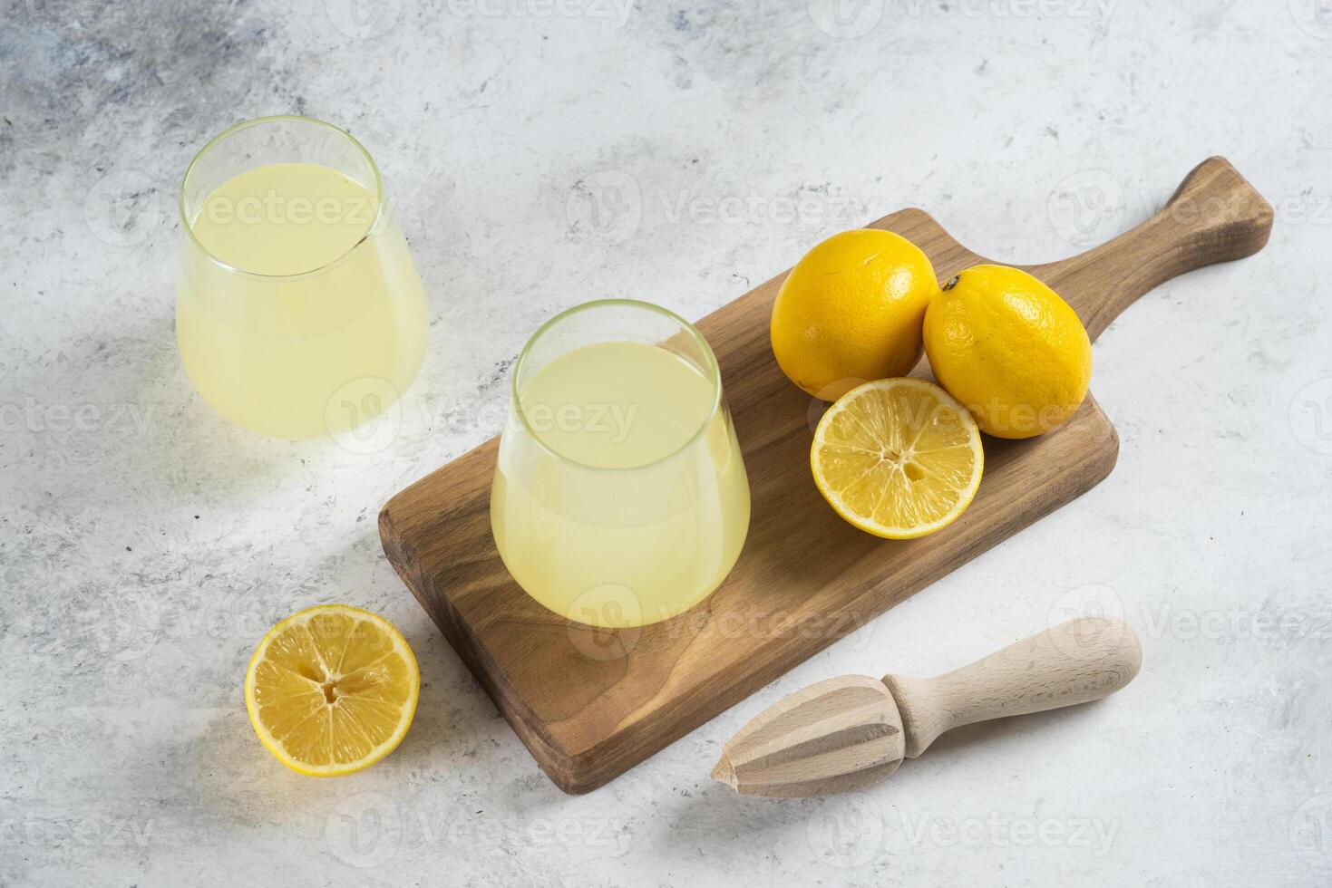 Two glass cups of lemonade and wooden reamer photo