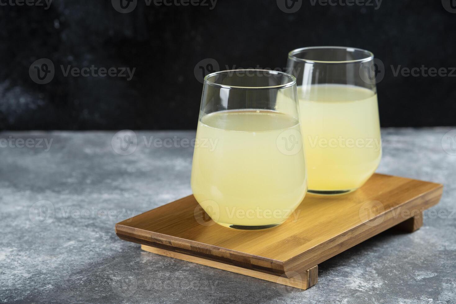 Two cups of lemonade on a wooden table background photo