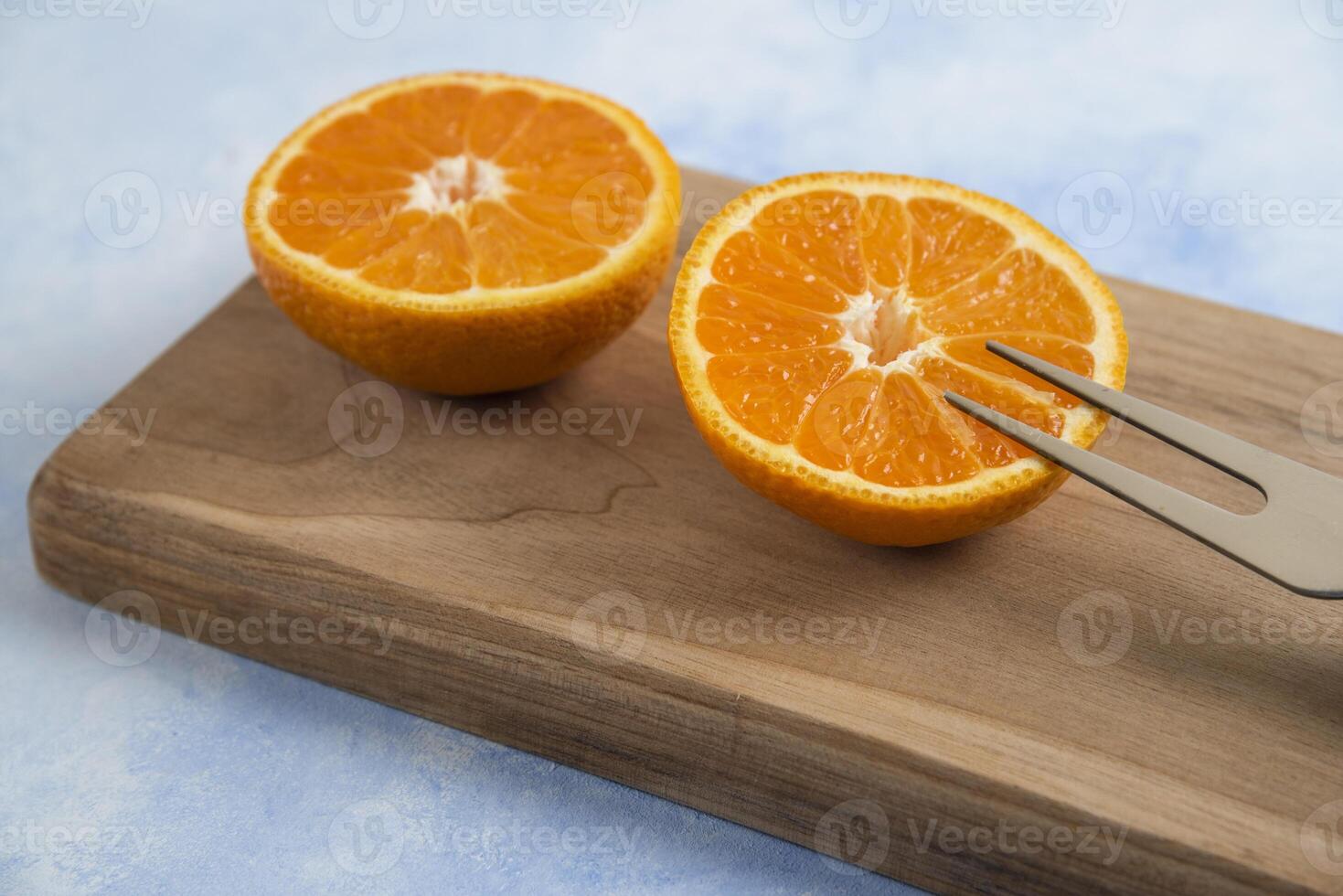 Close up photo of half cut clementine mandarin on wooden board