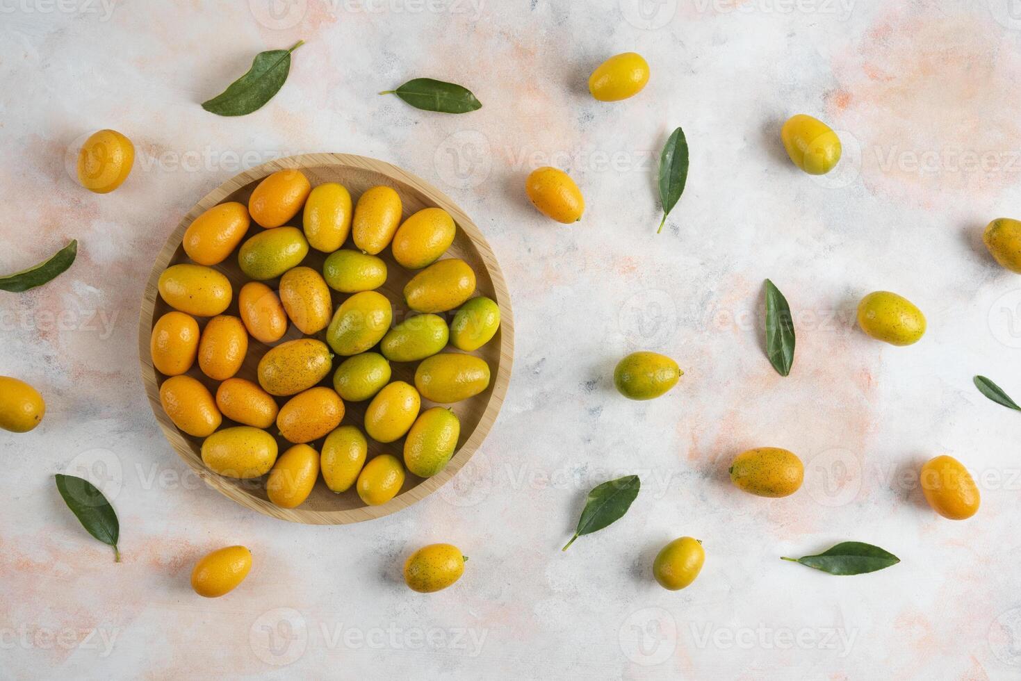 Top view, Pile of kumquats on wooden plate over colorful background photo