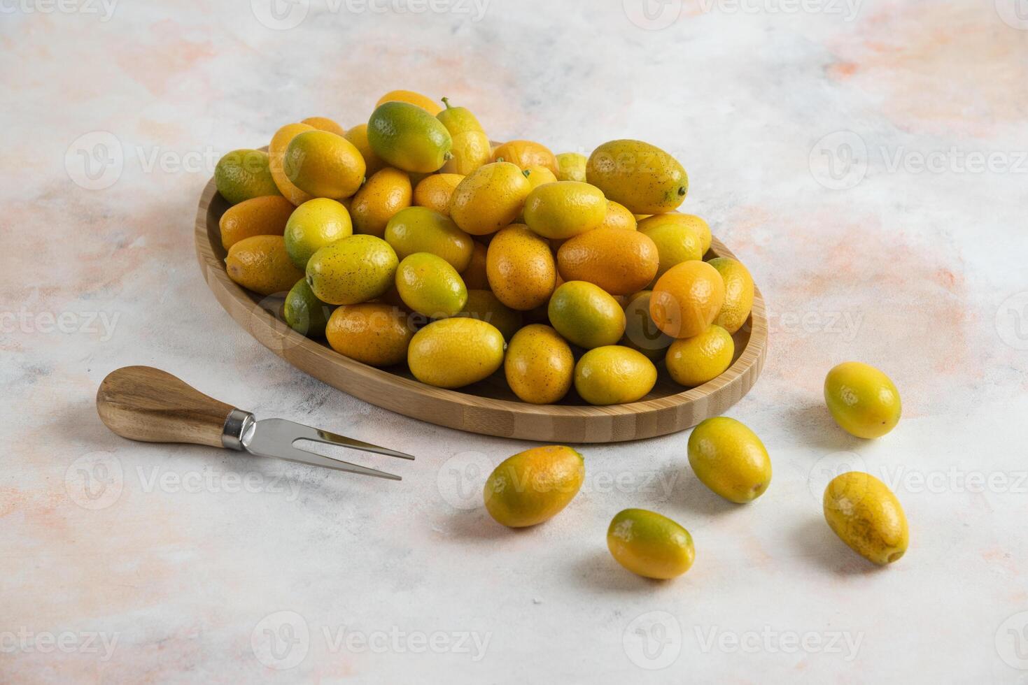 Pile of kumquats on wooden plate photo