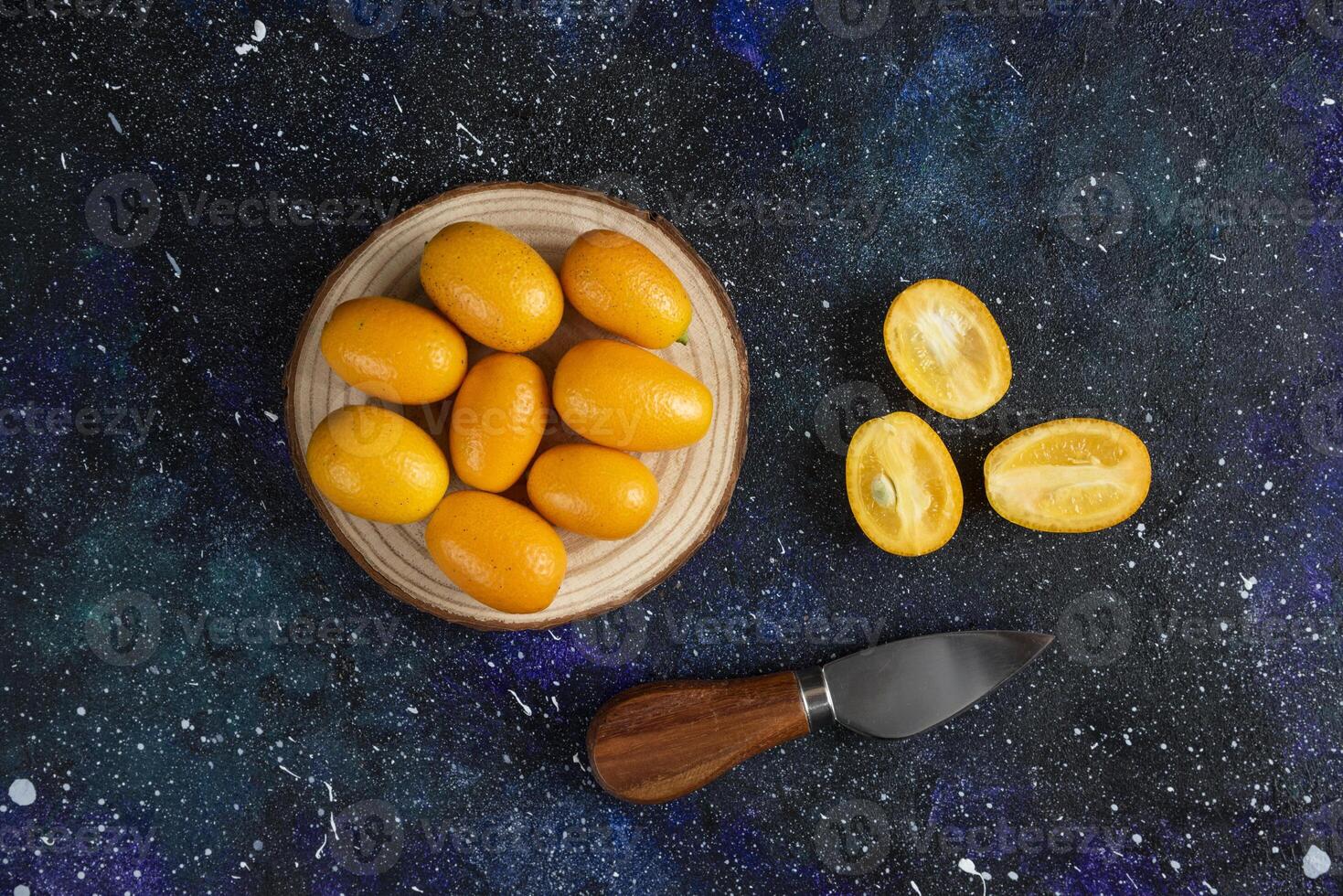 Top view of fresh kumquats on wooden board photo