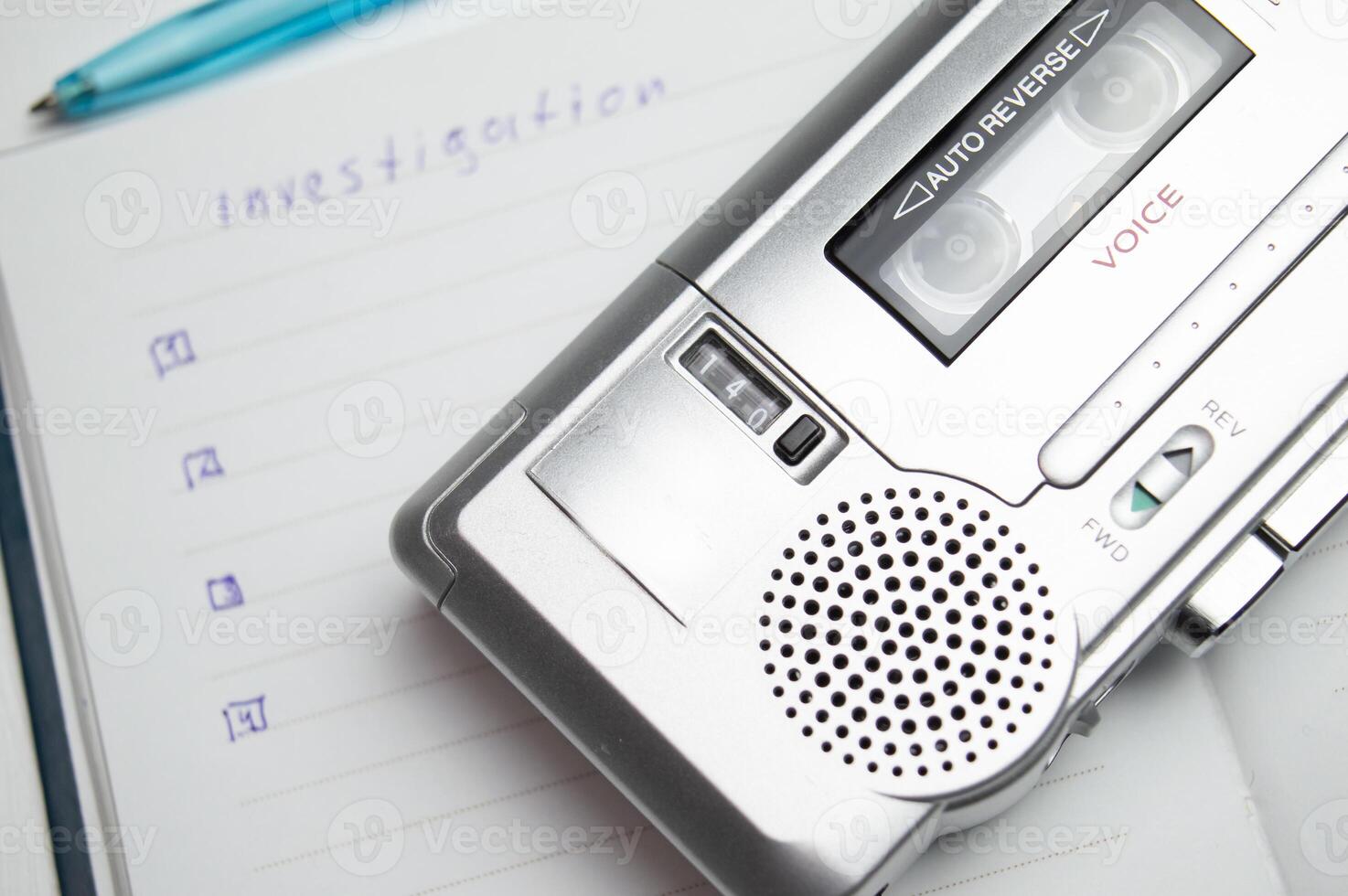 A tape recorder with buttons is on a notebook labeled investigation. the white background and workspace of the student detective professor. High quality photo
