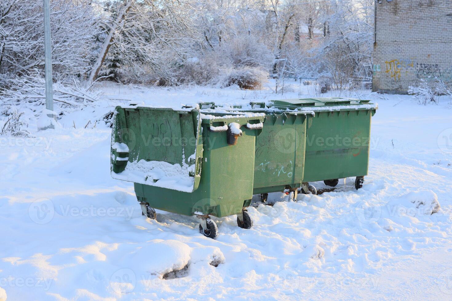 A beautiful winter scene featuring snowcovered trash bins that are colored green in a city photo