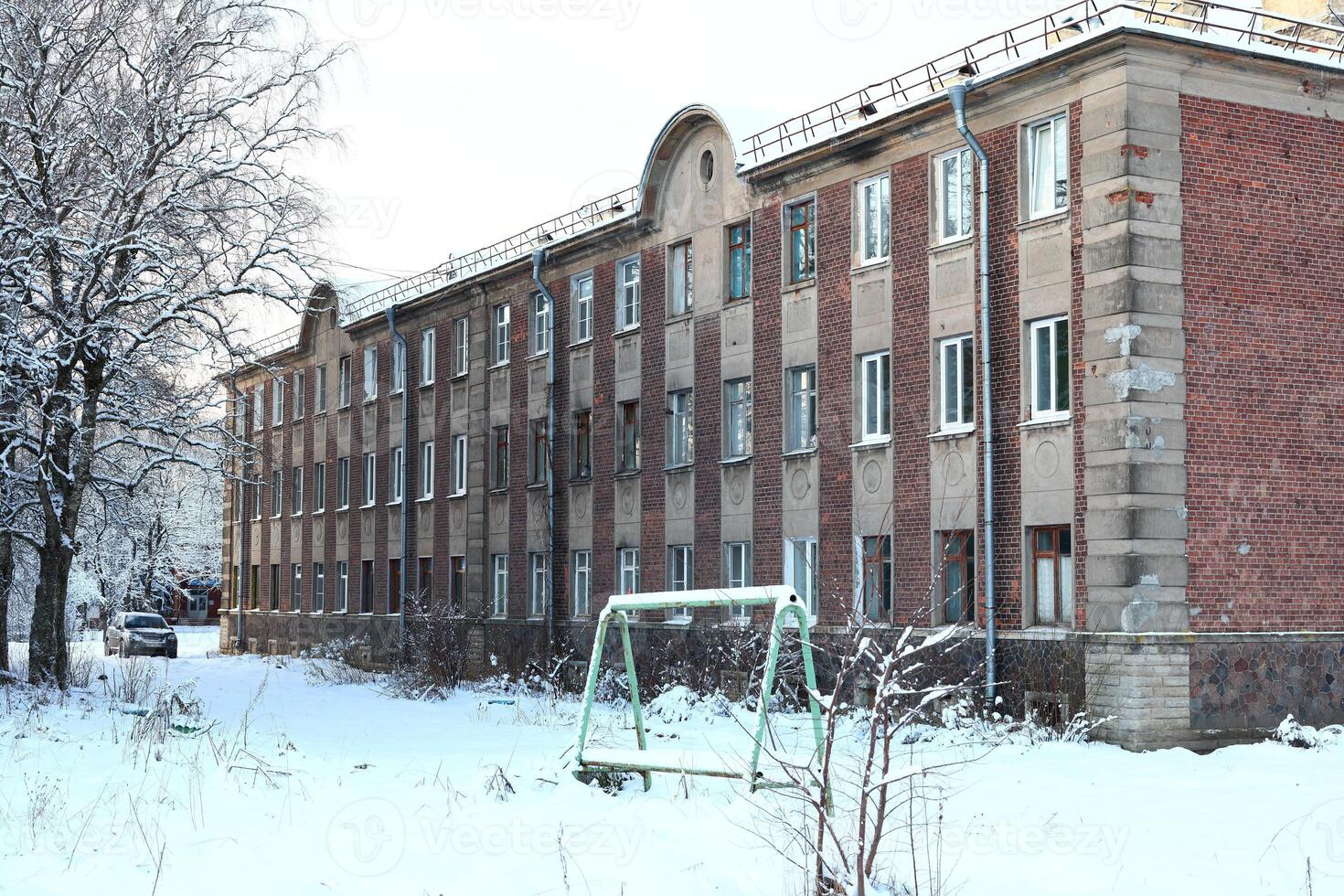 An Abandoned Building Surrounded by a Beautiful Winter Landscape in a Gloomy Setting photo